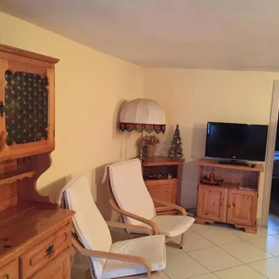 a living room with two white chairs and a television at Appartamento il Nido in Moena