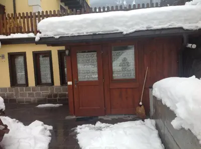 a house with a wooden door in the snow at Appartamento il Nido in Moena