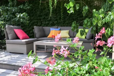 a couch with colorful pillows on a patio with flowers at Kröllnerhof in Lana