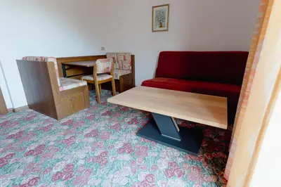 a living room with a red couch and a desk at Pension Lahn in Rablà