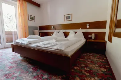 a bedroom with a large bed with white sheets at Pension Lahn in Rablà