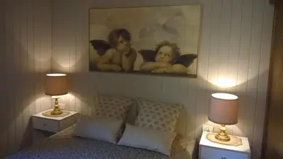 a bedroom with a bed with two lamps and a painting at Chalet Do Costa in Pozza di Fassa