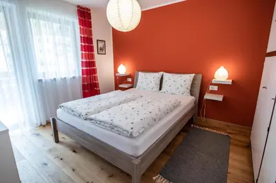 a bedroom with a bed with an orange wall at Apartment ARGENTIS Krumas-Living - Kronplatz in San Vigilio Di Marebbe
