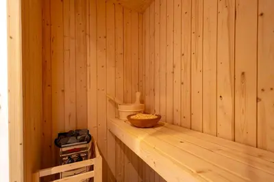a sauna with a wooden paneled wall and a wooden bowl at Apartment ARGENTIS Krumas-Living - Kronplatz in San Vigilio Di Marebbe