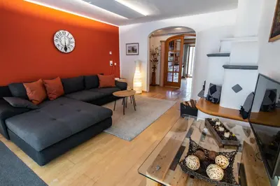 a living room with a couch and a clock on the wall at Apartment ARGENTIS Krumas-Living - Kronplatz in San Vigilio Di Marebbe