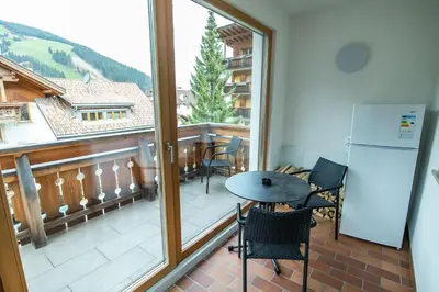 a balcony with a table and chairs and a large window at Apartment ARGENTIS Krumas-Living - Kronplatz in San Vigilio Di Marebbe