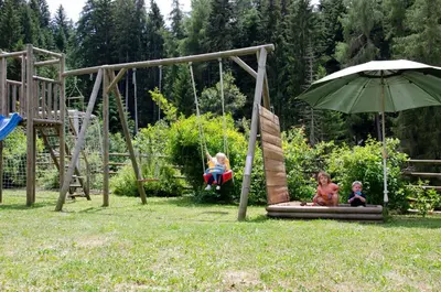 three children playing on a swing set with an umbrella at Schupferhof in Petersberg
