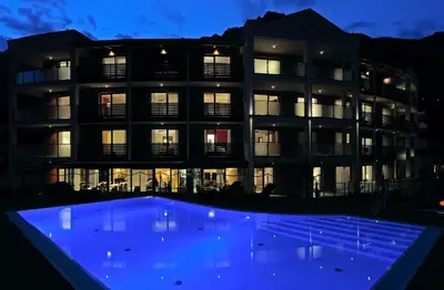 a building with a blue pool in front of it at ALIA appartements & wellness in Lagundo