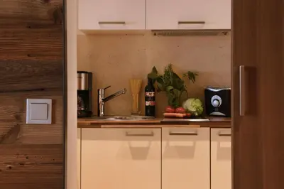 a kitchen with white cabinets and a sink at ALIA appartements & wellness in Lagundo