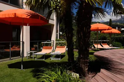 a group of chairs and umbrellas next to a building at ALIA appartements & wellness in Lagundo