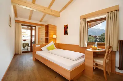 a bedroom with a bed and a desk and a window at Hotel und Residence Johanneshof in Cermes