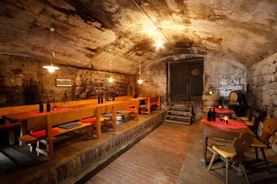 a restaurant with wooden tables and chairs in a cave at Hotel und Residence Johanneshof in Cermes