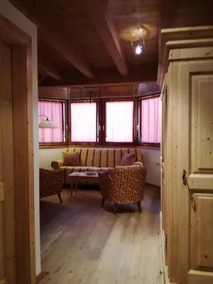 a living room with a couch and chairs and windows at Hotel Ca' del Bosco in Selva di Cadore