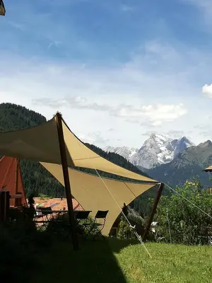 a tent in the grass with mountains in the background at Hotel Ca' del Bosco in Selva di Cadore