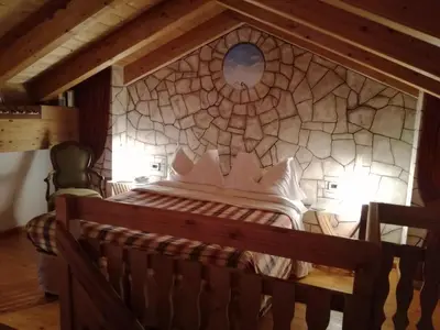 a bed in a room with a stone wall at Hotel Ca' del Bosco in Selva di Cadore