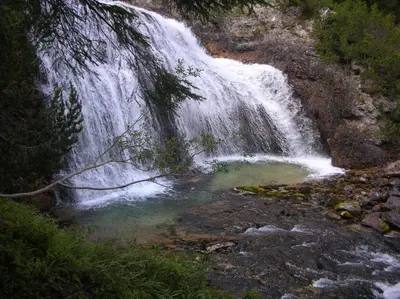 a waterfall with a pool of water in a river at Daniela Apartment in Cortina dʼAmpezzo