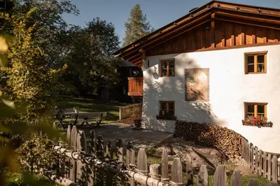 a white house with a wooden roof and a fence at Chalet Hafling Leckplått in Avelengo
