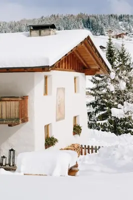 a house covered in snow with a tree at Chalet Hafling Leckplått in Avelengo