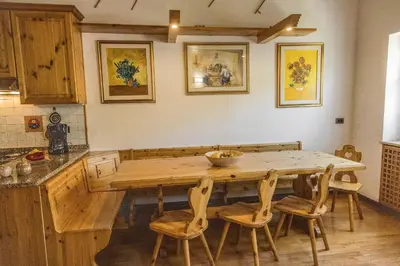 a kitchen with wooden cabinets and a dining room at Appartamento Sellaronda in Arabba