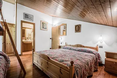 a bedroom with two beds and a ladder at Appartamento Sellaronda in Arabba