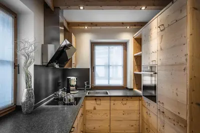 a kitchen with wooden cabinets and a sink and a window at Liondes Chalets in San Vigilio Di Marebbe