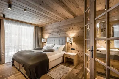 a bedroom with a bed and a wooden wall at Liondes Chalets in San Vigilio Di Marebbe