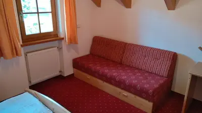 a red couch in a small room with a window at Oberlindnerhof in San Lorenzo di Sebato