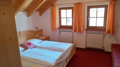 a bedroom with a bed and two windows at Oberlindnerhof in San Lorenzo di Sebato