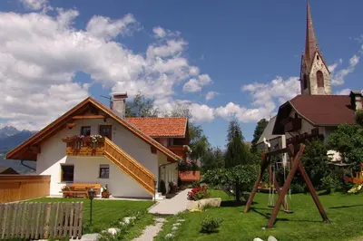 a church and a playground in front of a house at Oberlindnerhof in San Lorenzo di Sebato