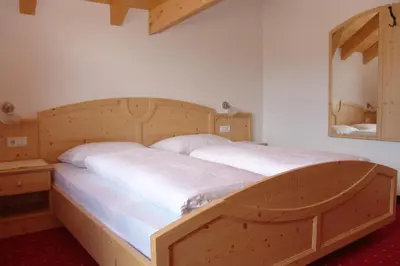 a large wooden bed in a room with a mirror at Oberlindnerhof in San Lorenzo di Sebato