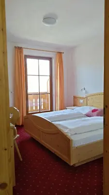 a large wooden bed in a room with a window at Oberlindnerhof in San Lorenzo di Sebato