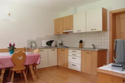 a kitchen with a table and a kitchen with white cabinets at Oberlindnerhof in San Lorenzo di Sebato