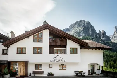 a large white building with mountains in the background at Residence Mirabell in Colfosco