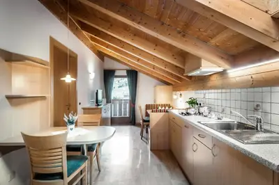 a kitchen with wooden ceilings and a table and chairs at Residence Mirabell in Colfosco