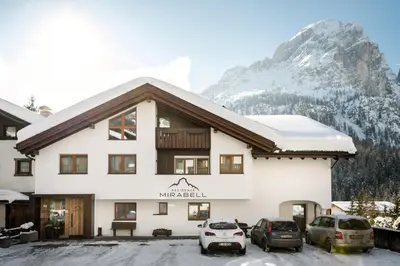 a building with two cars parked in a parking lot at Residence Mirabell in Colfosco