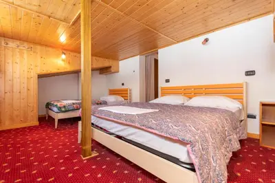 a bedroom with two beds and a red carpet at Villa Simona in Falcade