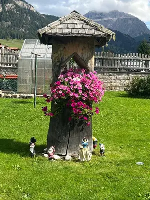 a tree stump with a planter with pink flowers at Mes Lastei in Campitello di Fassa