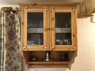 a wooden cabinet with dishes in it next to a curtain at Mes Lastei in Campitello di Fassa