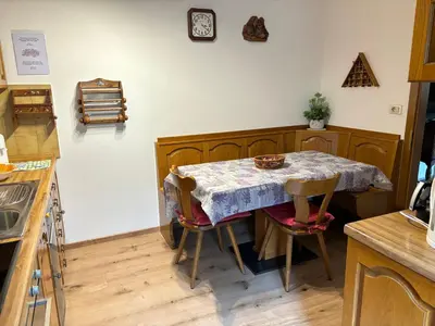 a kitchen with a table with chairs and a clock on the wall at Mes Lastei in Campitello di Fassa
