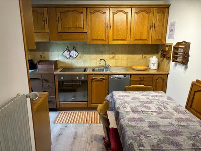 a kitchen with wooden cabinets and a sink and a table at Mes Lastei in Campitello di Fassa