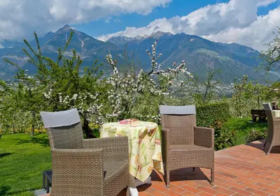 a table and chairs with mountains in the background at Pension Planta in Merano