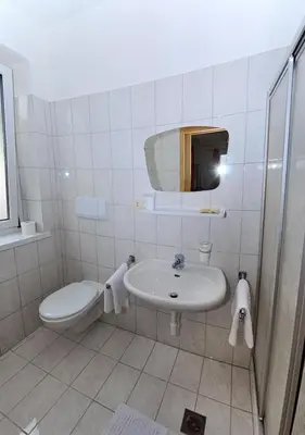 a white bathroom with a sink and a toilet at Pension Planta in Merano