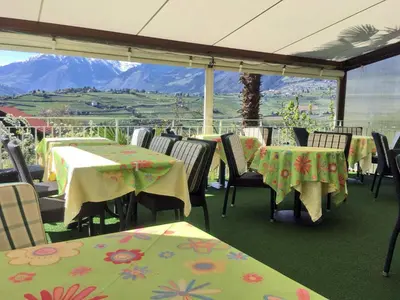 a restaurant with tables and chairs with a view of mountains at Pension Planta in Merano