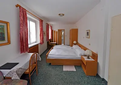 a bedroom with a large white bed and two windows at Pension Planta in Merano