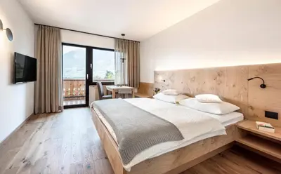 a bedroom with a large bed and a large window at Pension Appartment Hecherhof in Merano
