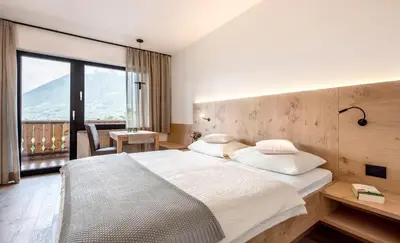 a bedroom with a large bed and a large window at Pension Appartment Hecherhof in Merano