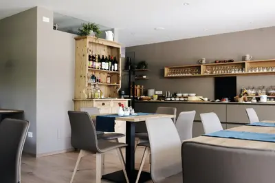 a dining room with tables and chairs and a kitchen at Pension Appartment Hecherhof in Merano