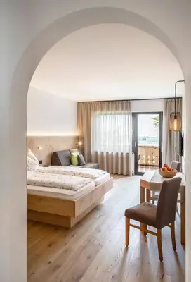 a bedroom with a bed and a table and a chair at Pension Appartment Hecherhof in Merano
