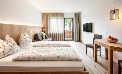 a hotel room with two beds and a table at Pension Appartment Hecherhof in Merano
