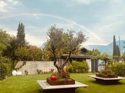 a rainbow in the sky above a yard at Hotel Garni Vinea Montis in Termeno
